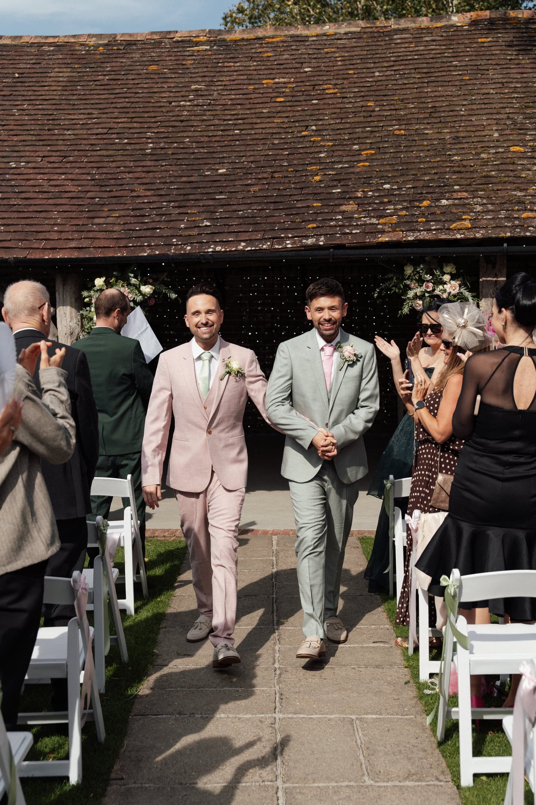 Ronnie and Danny walking up the aisle together during their ceremony at Winters Barns