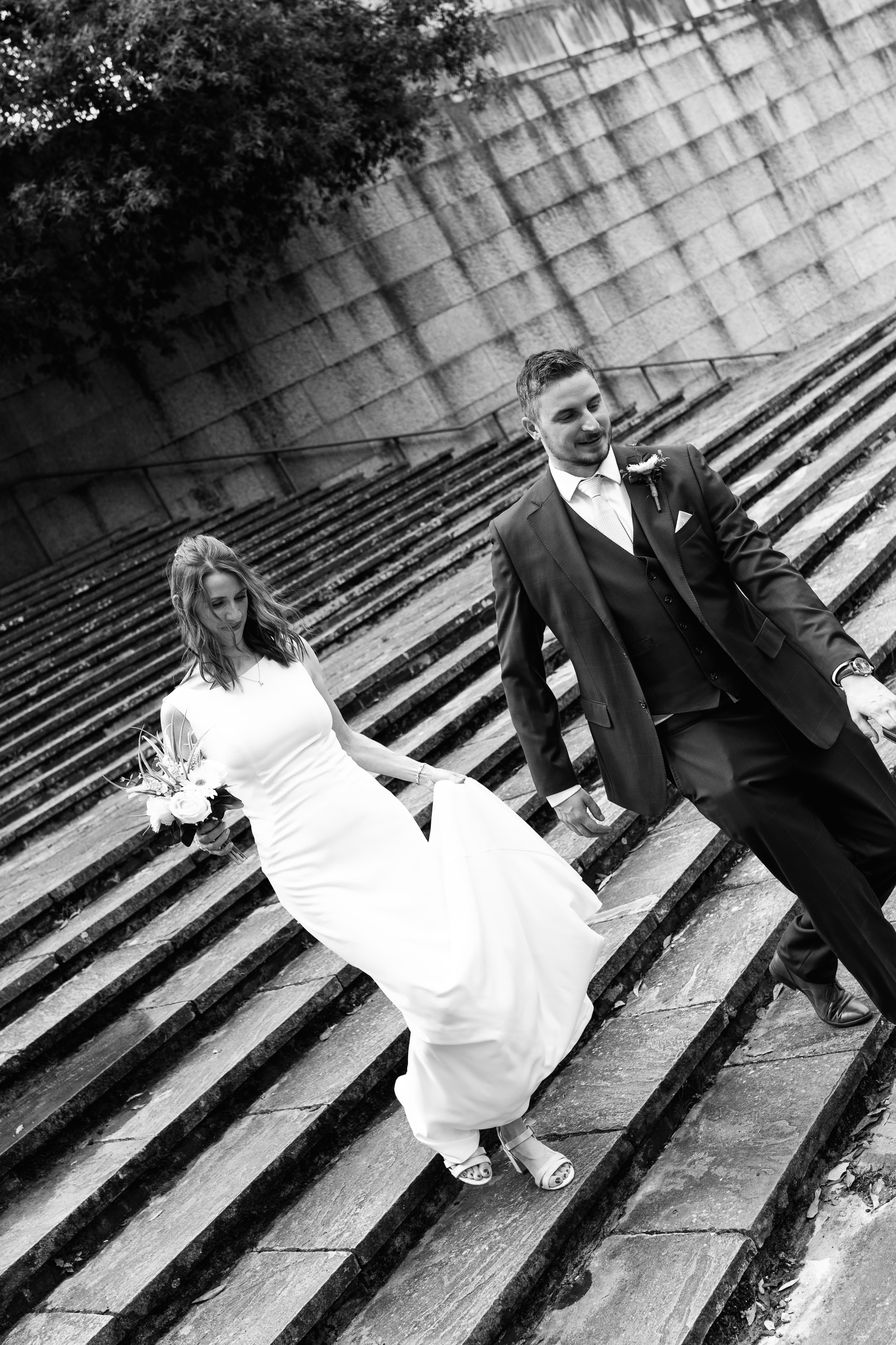 Bride and groom walking hand in hand in black and white wedding photo